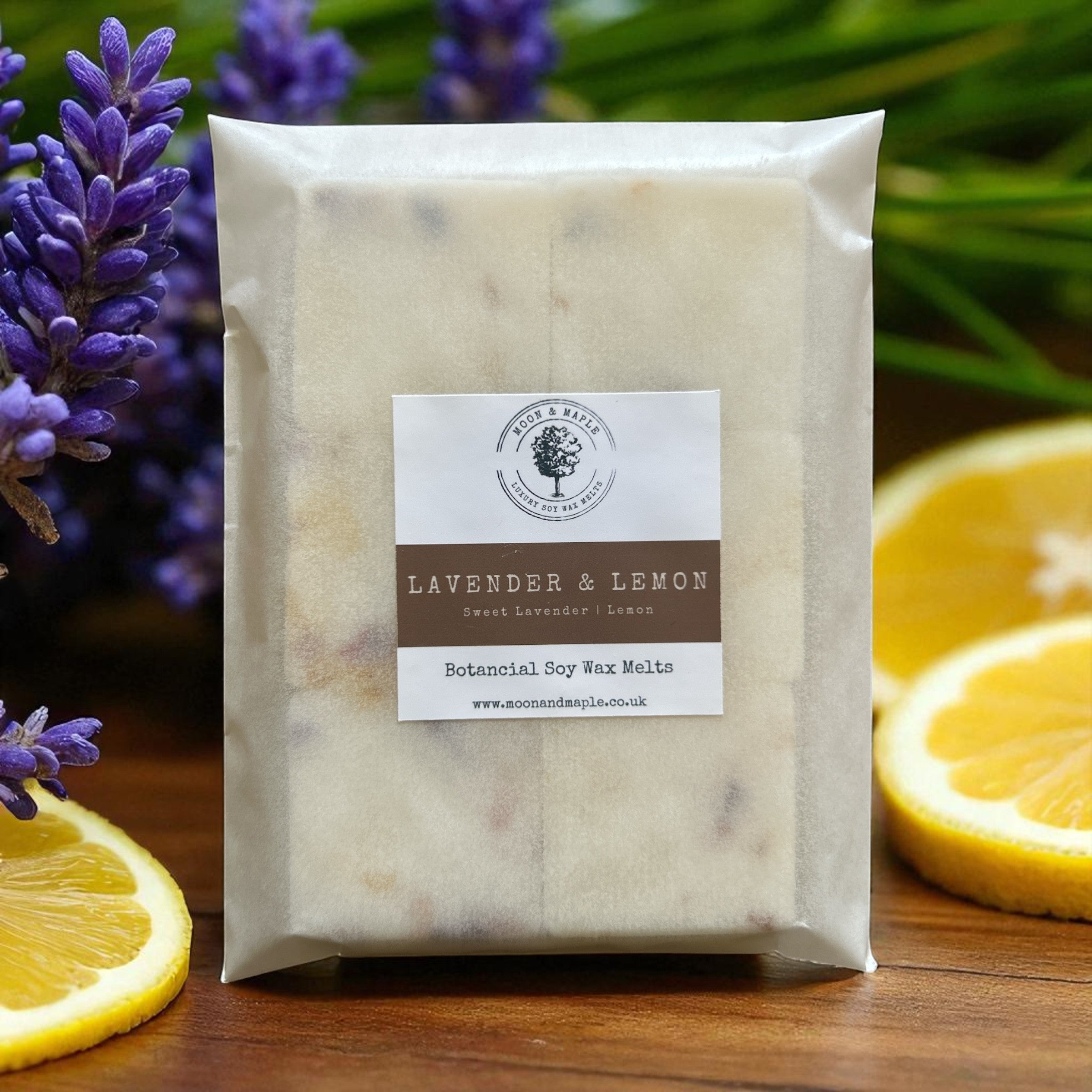 Packaged lavender and lemon wax melts with a label on a wooden surface with lavender and lemon slices.