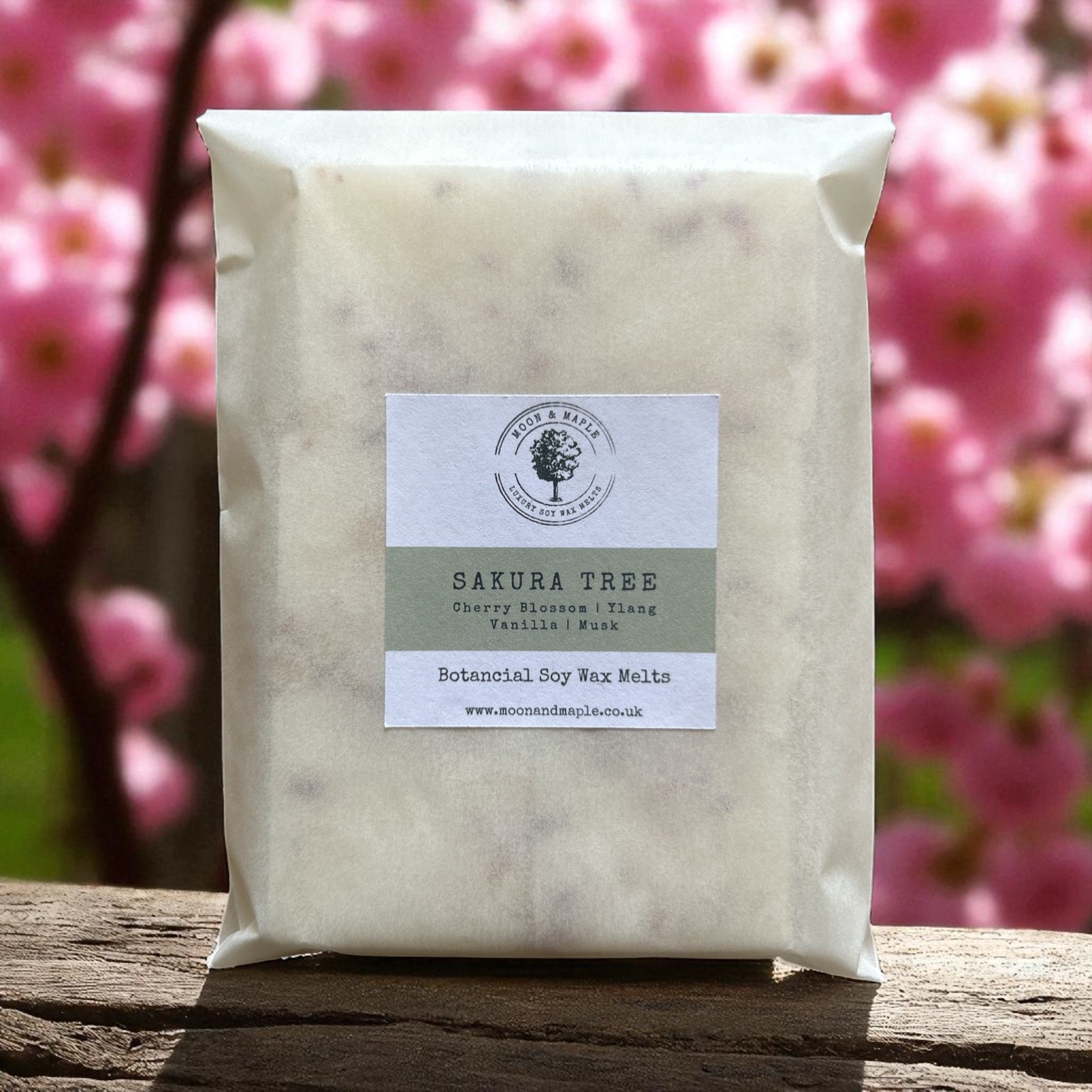 Pack of Sakura Tree botanical soy wax melts with a cherry blossom tree in the background