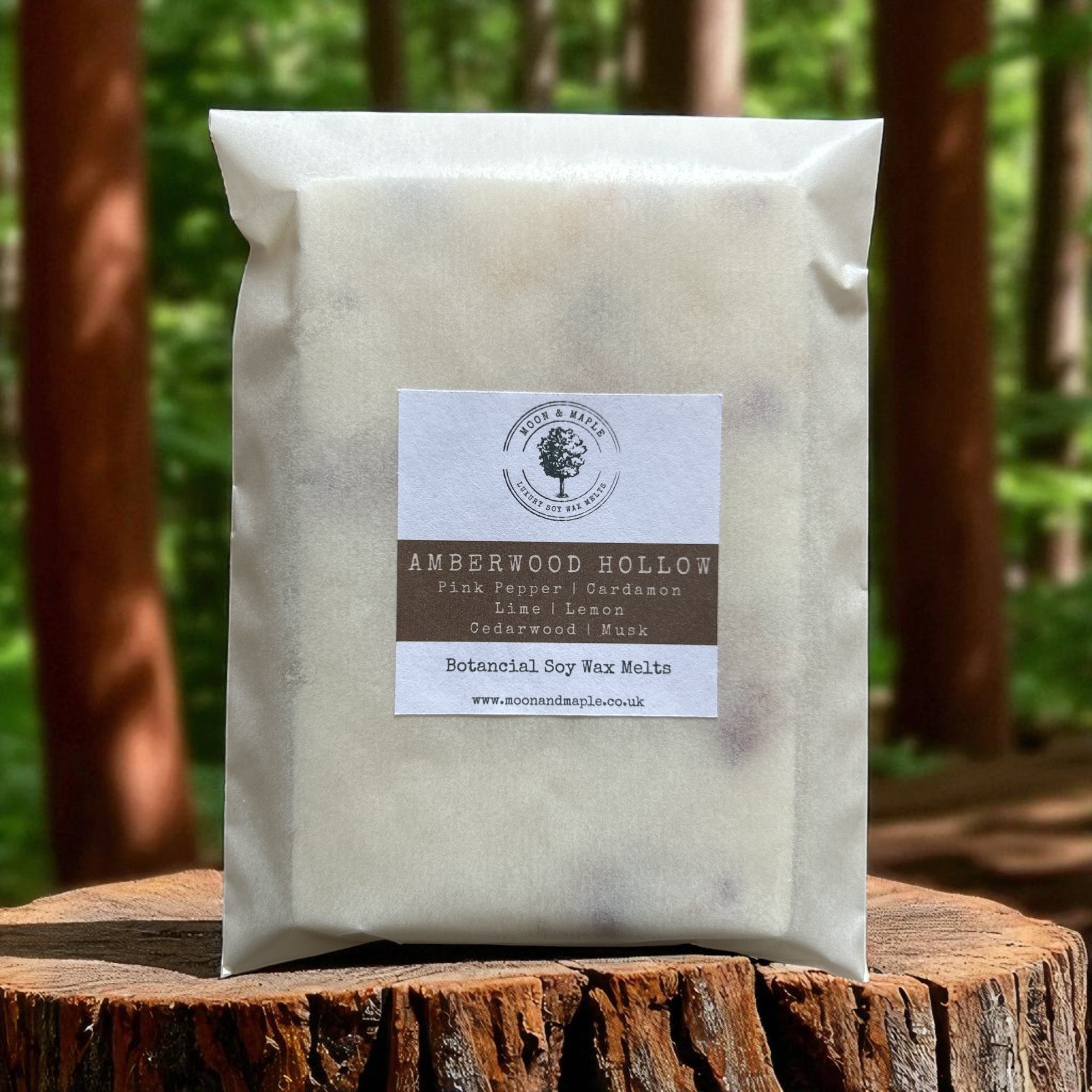 Package of Amberwood Hollow wax melts on a wooden log with a forest background