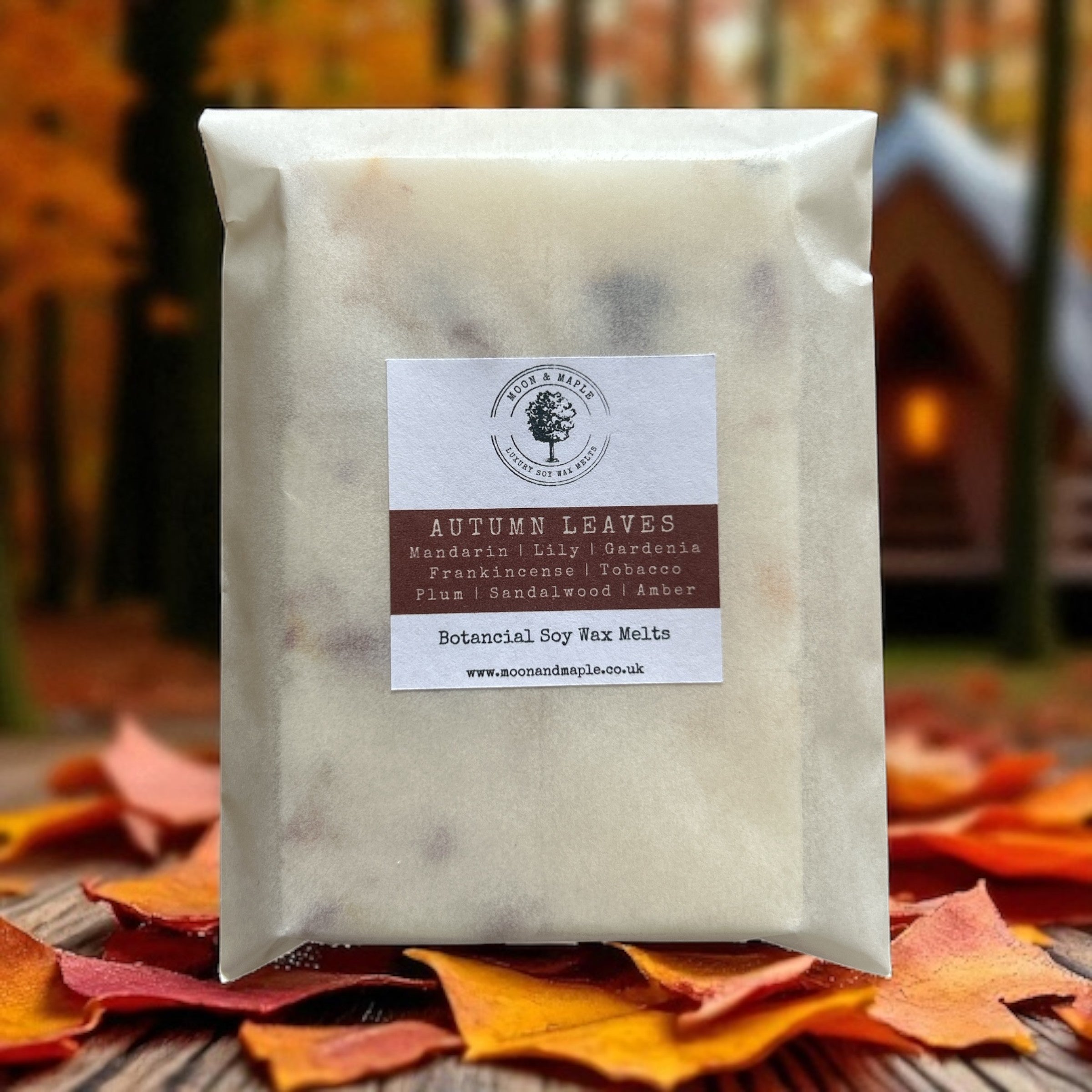 Pack of 'Autumn Leaves' wax melts with a label on a background of autumn leaves and a blurred cabin.