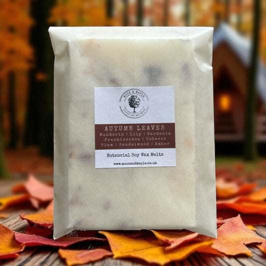 Pack of 'Autumn Leaves' wax melts with a label on a background of autumn leaves and a blurred cabin.