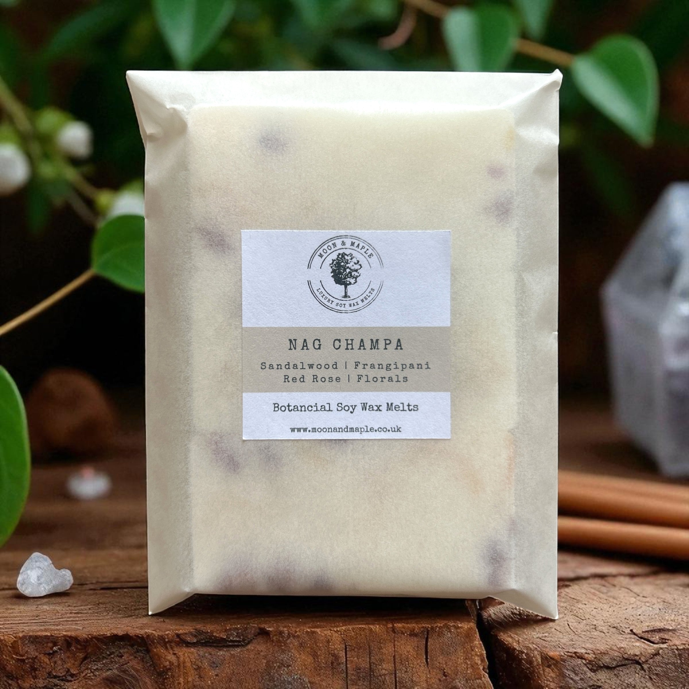 Packaged wax melts with a label on a wooden surface with greenery in the background