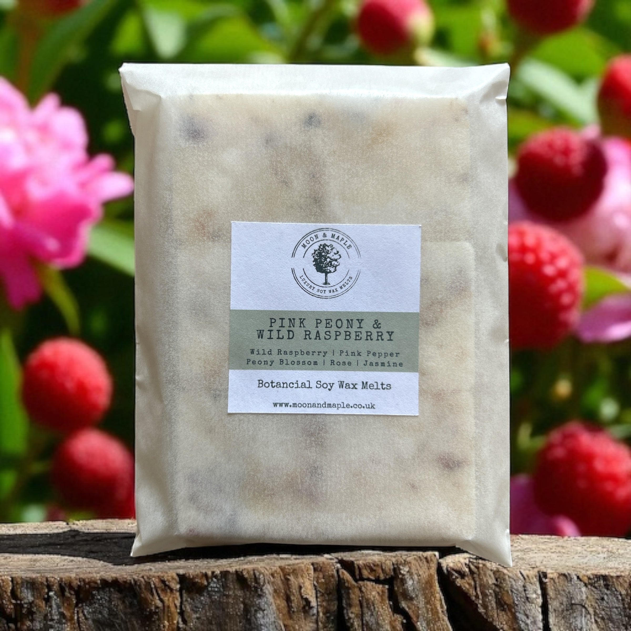 Pack of Pink Peony and Wild Raspberry wax melts on a wooden surface with flowers in the background