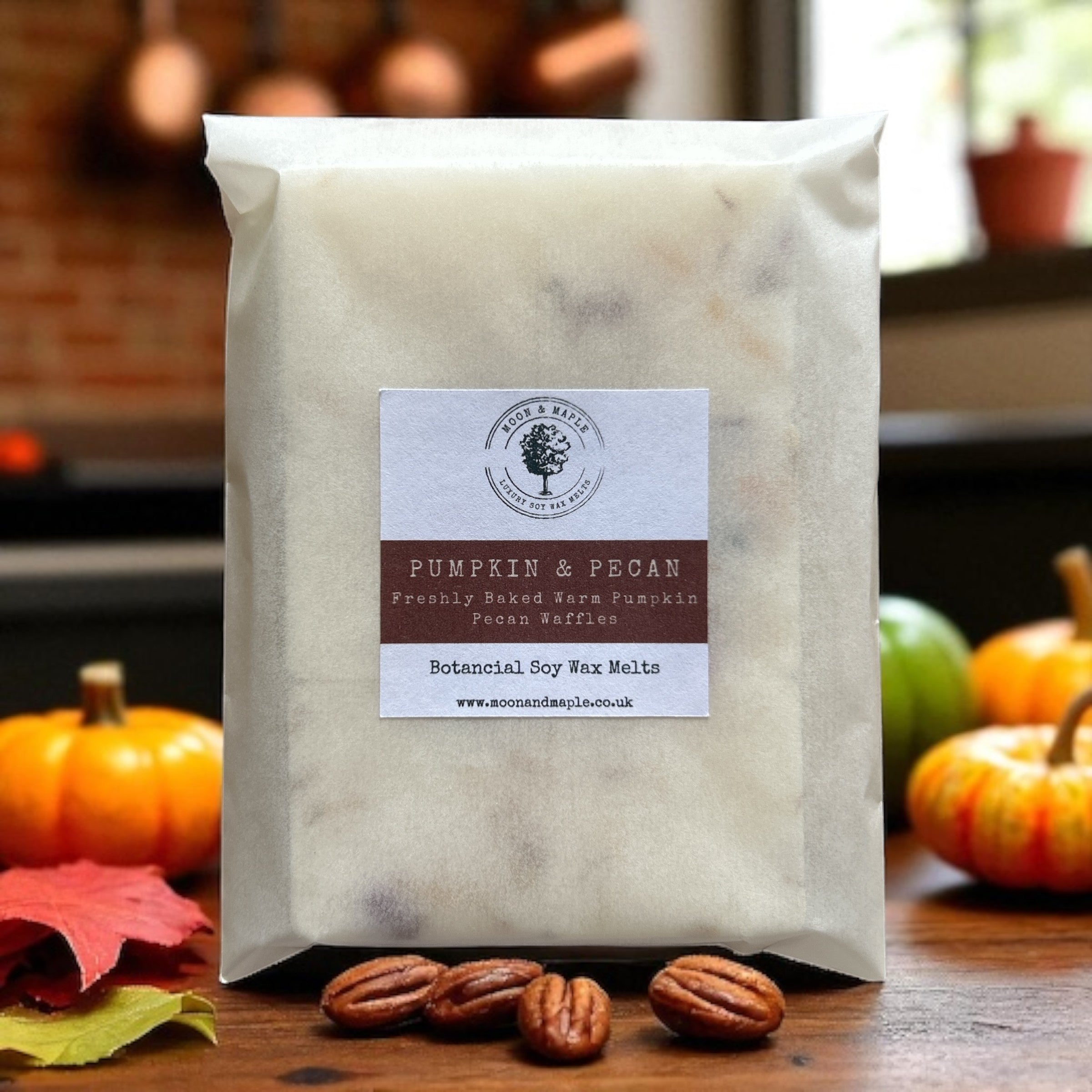 Bag of pumpkin and pecan wax melts with a label on a wooden surface with pumpkins and leaves.