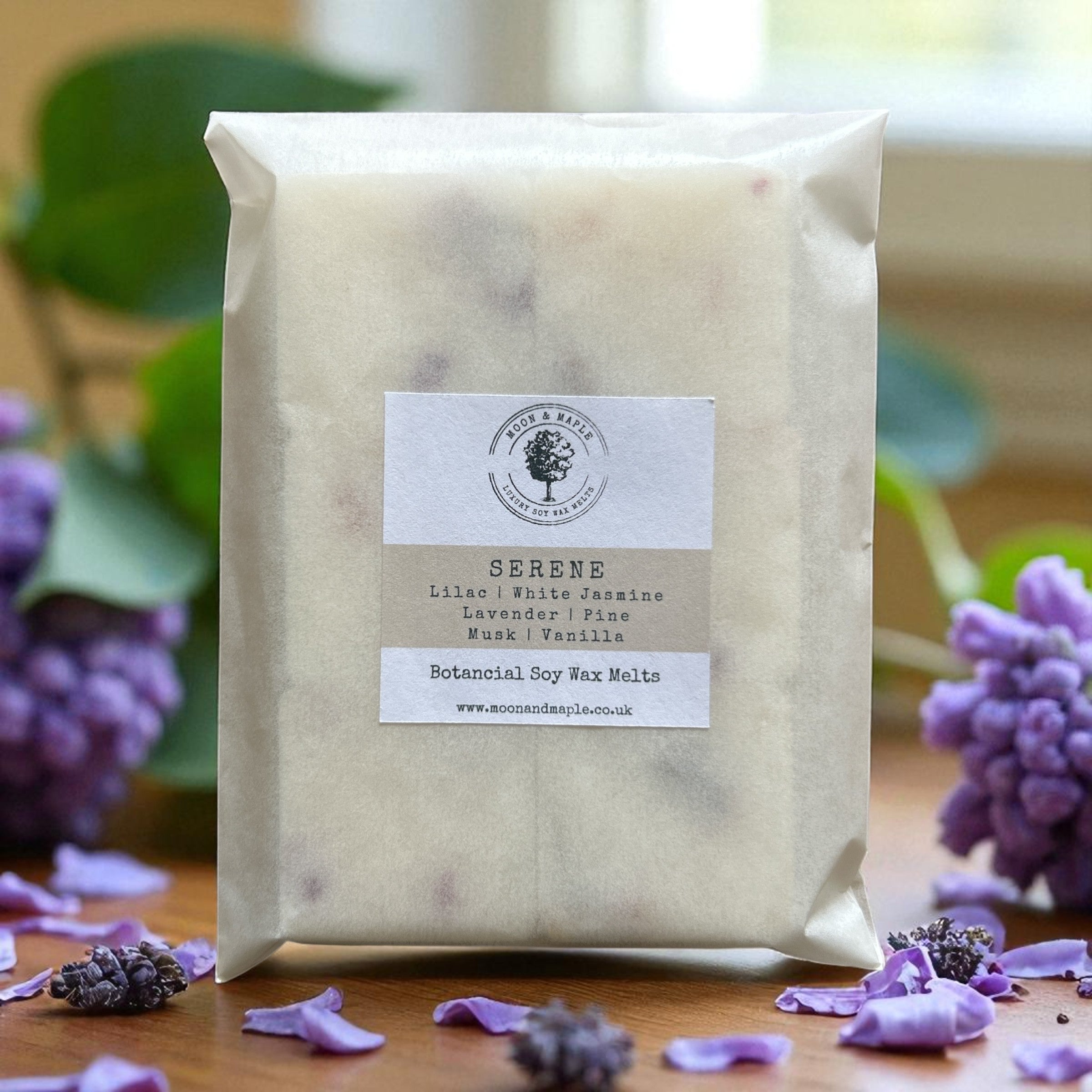 Pack of Serene botanical soy wax melts with lavender and vanilla scents, surrounded by purple flowers on a wooden surface.
