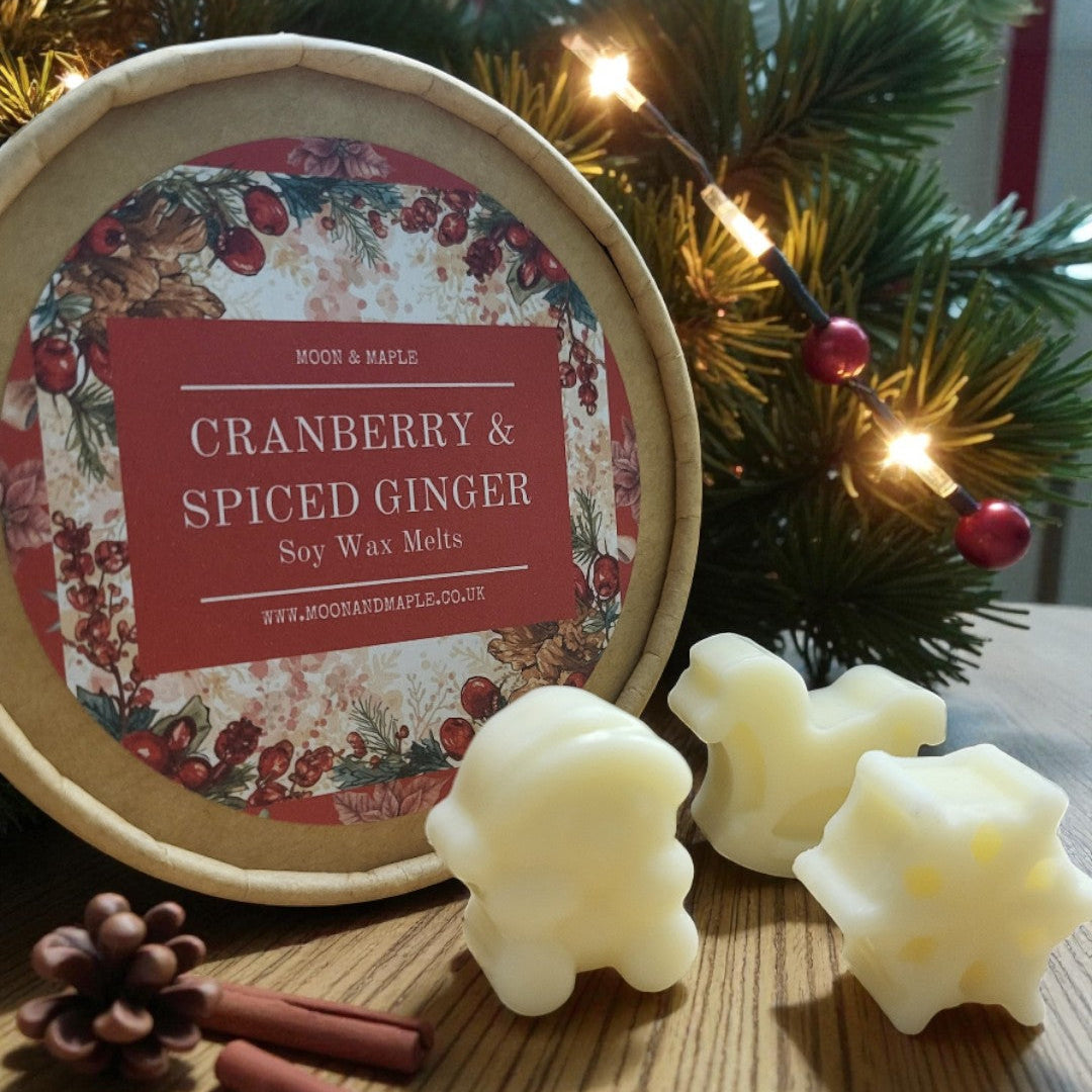 Cranberry & Spiced Ginger soy wax melts with packaging on a wooden surface, surrounded by Christmas decorations.